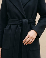 The Caroline Tie Waist Coat in black — close-up of the tie waist belt and patch pocket