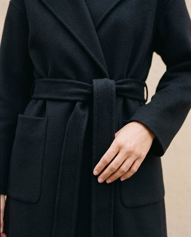 The Caroline Tie Waist Coat in black — close-up of the tie waist belt and patch pocket