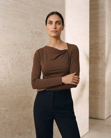 The Celeste Asymmetrical Long Sleeve Top in coffee — asymmetric-neck long-sleeve top, three-quarter view on model