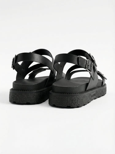 The Celeste Sandal in black — buckled strap sandals with lug platform sole, three-quarter pair view