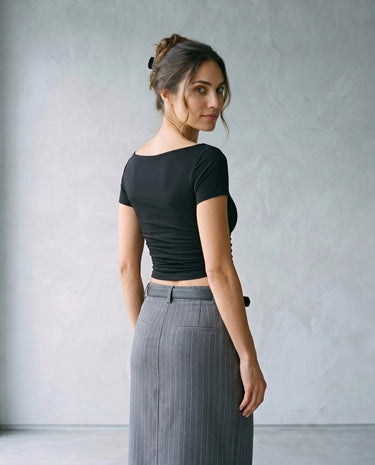 Model wearing black boat-neck top with grey skirt, back view over the shoulder – Moriel Heritage