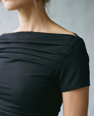 Close-up of black boat-neck top showing wide neckline and pintuck pleating across the shoulder – Moriel Heritage