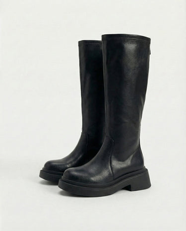 The Elara Slim Riding Boots in black — knee-high riding boots, angled view