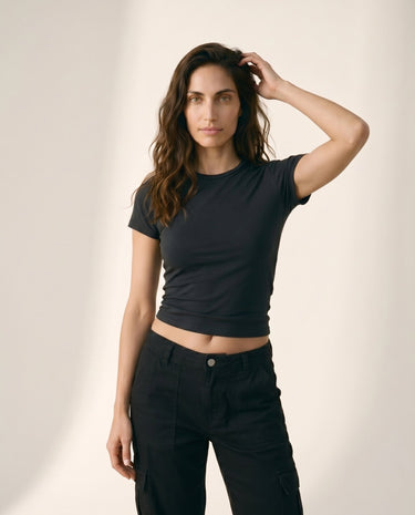 Model wearing black cropped crew-neck tee, arm raised front view – Moriel Heritage