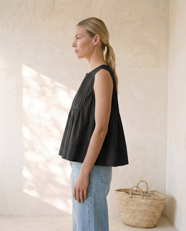 The Elio Pleat Vest in black — pleated swing top, side view on model