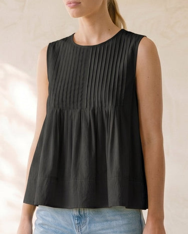 The Elio Pleat Vest in black — sleeveless pleated swing top, front view on model