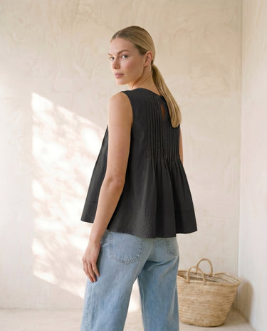 The Elio Pleat Vest in black — pleated swing top, side view on model