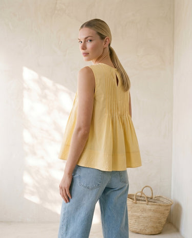 The Elio Pleat Vest in yellow — pleated swing top, side view on model