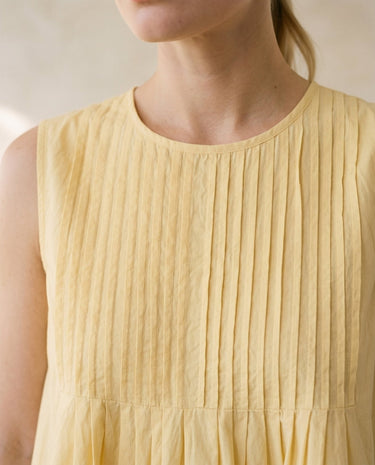 The Elio Pleat Vest in yellow — close-up of pin-tuck pleated neckline