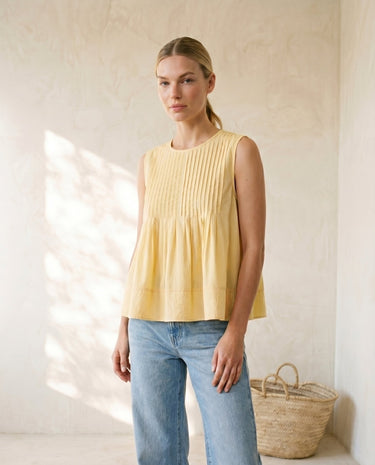 The Elio Pleat Vest in yellow — sleeveless pleated swing top, front view on model