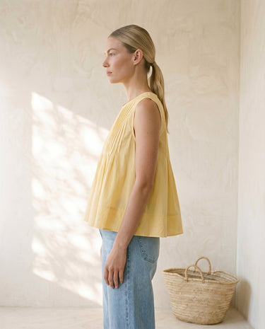 The Elio Pleat Vest in yellow — pleated swing top, side view on model