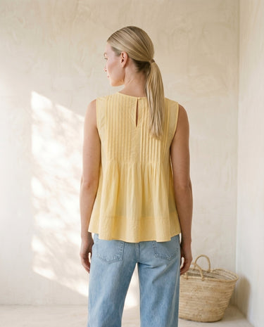 The Elio Pleat Vest in yellow — pleated swing top, back view on model