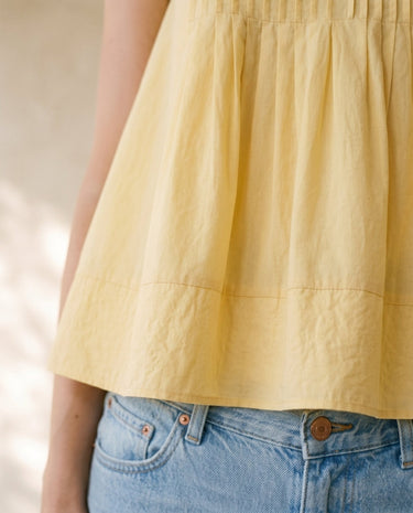 The Elio Pleat Vest in yellow — close-up of pleated hem