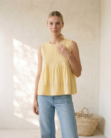 The Elio Pleat Vest in yellow — sleeveless pleated swing top, front view on model