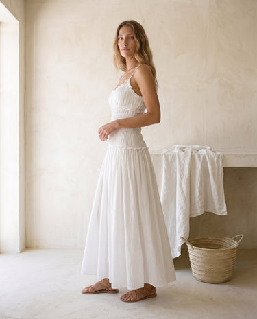 The Elire Dress in white — shirred maxi dress with tiered skirt, side view on model