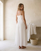 The Elire Dress in white — shirred maxi dress with tiered skirt, back view on model