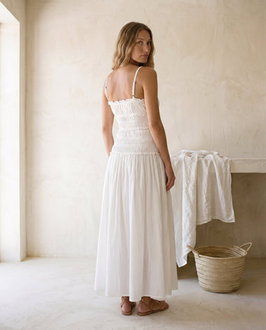 The Elire Dress in white — shirred maxi dress with tiered skirt, back view on model