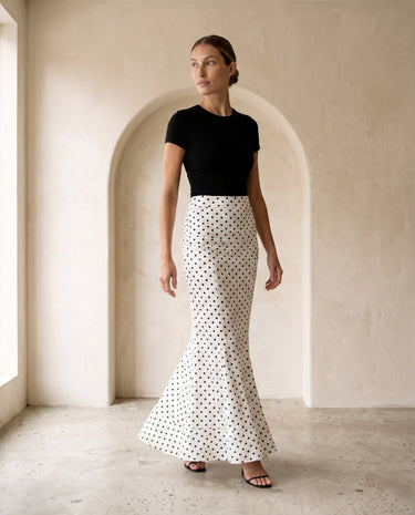 The Elisia Polka Dot Skirt in white — polka dot fishtail maxi skirt, full-length front view on model