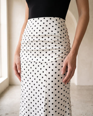 The Elisia Polka Dot Skirt in white — close-up of ruched high waist and black polka dot detail