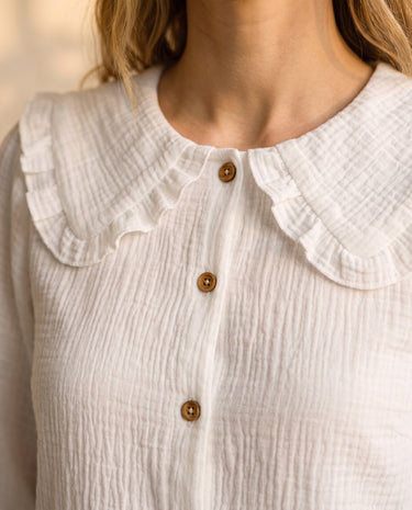 The Elodie Cotton Ruffle Collar Blouse in white — close-up of oversized ruffle collar and wooden buttons