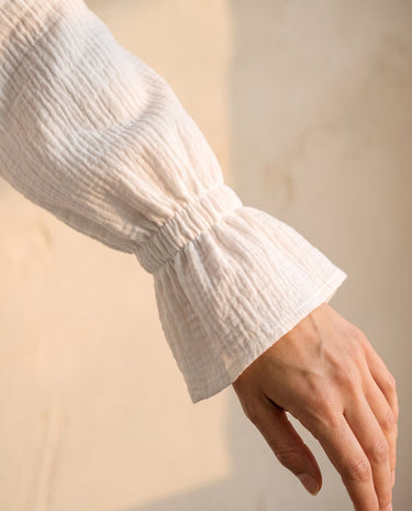 The Elodie Cotton Ruffle Collar Blouse in white — close-up of ruffle-cuff long sleeve