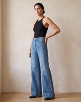 The Elodie jeans in blue — front three-quarter view with hand on hip on model