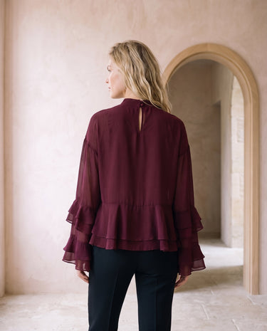 The Eloise Ruffle Blouse in burgundy — ruffle-sleeve blouse, back view on model