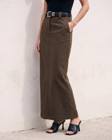 The Eloise Tailored Skirt in brown — straight maxi skirt with hand in pocket, front view on model