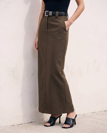 The Eloise Tailored Skirt in brown — straight maxi skirt with hand in pocket, front view on model
