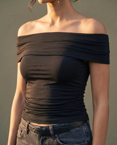 Model wearing black off-shoulder top with jeans, cropped front view – Moriel Heritage