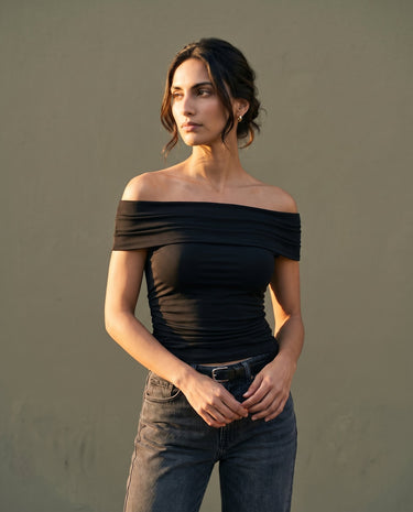 Model wearing black off-shoulder top with jeans, front view – Moriel Heritage