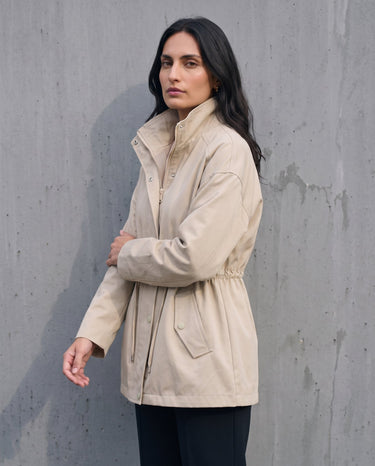 Side view of the light khaki Halden Coat showing the stand collar and hip-length hem