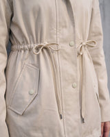 Close-up of the Halden Coat's drawstring waist, press-stud placket and slanted welt pocket in light khaki