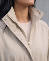Close-up of the Halden Coat's stand collar, concealed hood and two-way zip in light khaki