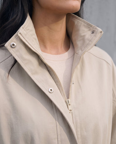 Close-up of the Halden Coat's stand collar, concealed hood and two-way zip in light khaki