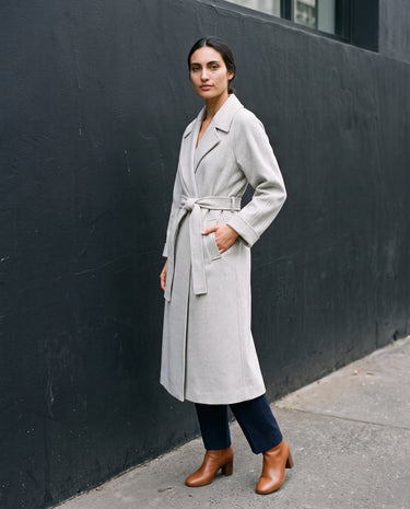 The Haven Tie Waist Coat in light gray — long wrap coat, front view with hand in pocket on model
