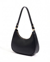The Ines Crescent Bag in black, three-quarter studio view showing the half-moon silhouette and gold-tone hardware