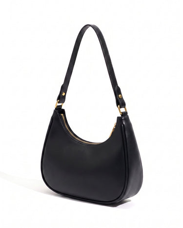 The Ines Crescent Bag in black, three-quarter studio view showing the half-moon silhouette and gold-tone hardware