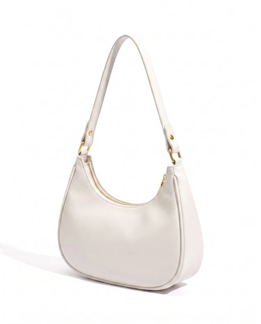 The Ines Crescent Bag in white, three-quarter studio view showing the half-moon silhouette and gold-tone hardware