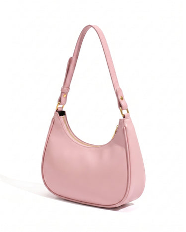 The Ines Crescent Bag in pink, three-quarter studio view showing the half-moon silhouette and gold-tone hardware