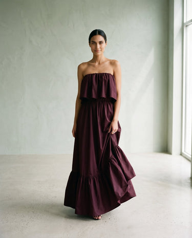 The Ivy Maxi in burgundy — strapless tiered maxi dress, front view with flowing skirt on model