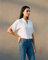 Model wearing the white blouse against a sunlit wall, front view – Moriel Heritage
