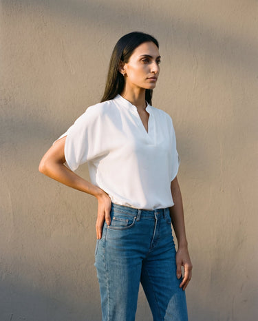Model wearing the white blouse against a sunlit wall, front view – Moriel Heritage