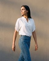 Model walking in the white blouse and jeans, three-quarter view – Moriel Heritage