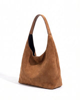 The Léa Slouch Tote in brown suede, three-quarter studio view showing the slouched body and single wide shoulder strap