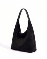 The Léa Slouch Tote in black suede, three-quarter studio view on a white background