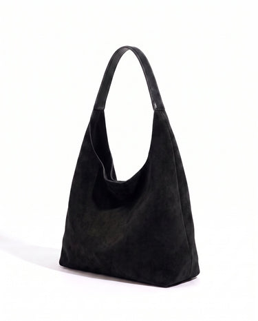 The Léa Slouch Tote in black suede, three-quarter studio view on a white background