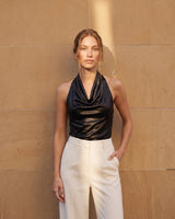 Model wearing the black cowl-neck halter top with wide-leg cream trousers – Moriel Heritage