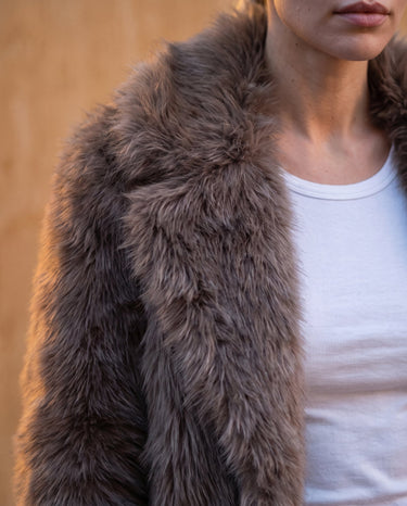 Close-up of the Lira Jacket's wide notch collar and long-pile faux fur texture in dark brown
