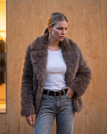 Model wearing the dark brown faux fur Lira Jacket open, front view in natural light